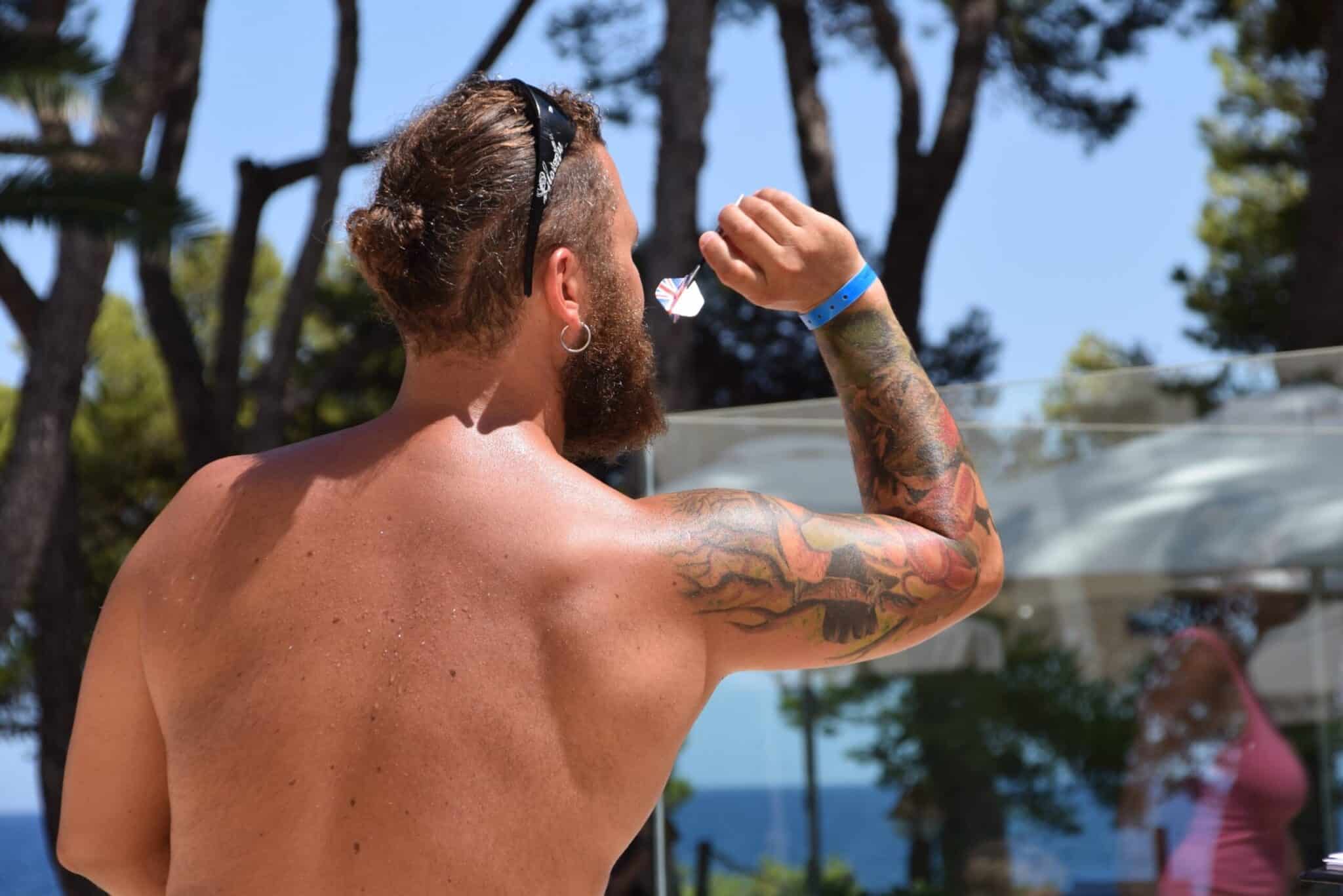 Dartspieler wirft Dartpfeil auf Steeldart Dartscheibe – Darts Fanshop Hintergrundbild